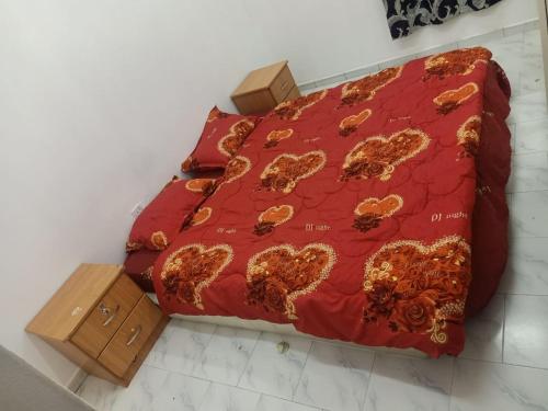 1 cama con edredón rojo y tabla de planchar de madera en Private room for upto 4 peope, en Sharjah