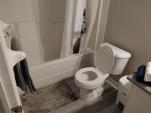 een witte badkamer met een toilet en een bad bij Lovely and calm townhouse with free parking in London