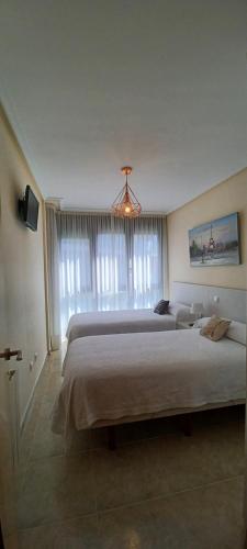 a large bedroom with two beds and a chandelier at La Escollera Noja in Noja