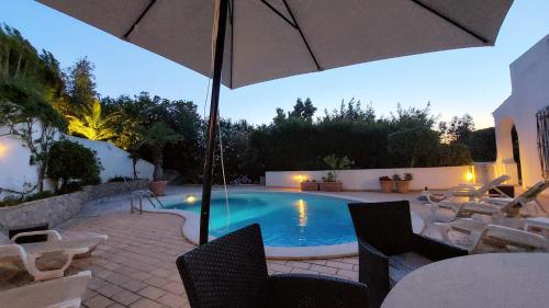 a swimming pool with chairs and an umbrella at Casa Jolie in Vale do Lobo