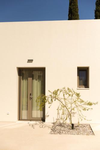 a tree in front of a white building with a door at Stablo Residence in Kanálion