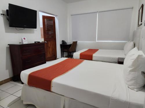 a hotel room with two beds and a television at Altamont West Hotel in Montego Bay