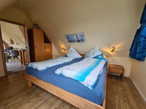 Schlafzimmer mit einem Bett mit blauer und weißer Bettwäsche in der Unterkunft Ferienwohnung Inselblick Norddeich mit Meerblick in Norden