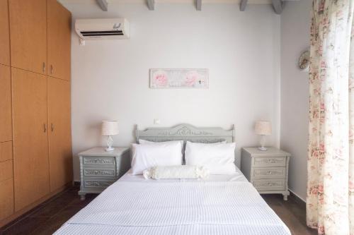 a bedroom with a white bed with two night stands at Green Garden in Porto Heli