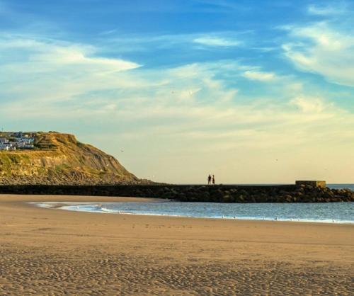 a beach with two people standing on a bluff at L’annexe sur mer in Le Portel