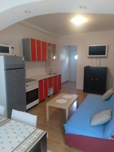 een keuken met rode kasten en een blauwe bank in een kamer bij Apartmani Binka in Petrcane