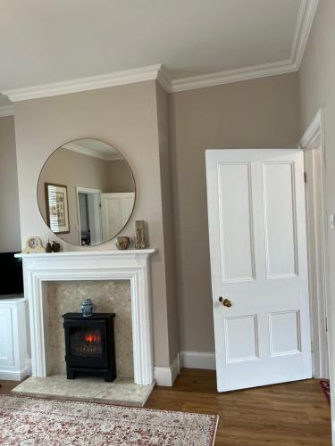 a living room with a fireplace and a mirror at The Lily Pad - Boutique Townhouse, a short walk to Town Center and Racecourse in Cheltenham
