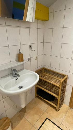 La salle de bains est pourvue d'un lavabo blanc et d'un panier. dans l'établissement Ferienhaus Gare de Mareuil, à Sainte-Croix-de-Mareuil