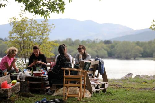 a group of people sitting at a picnic table by a lake at LAKE HOUSE 'VILIN KONAK' in Nikšić
