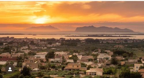 a city with a sunset and mountains in the background at Casa Vacanza Patrizia in Marsala