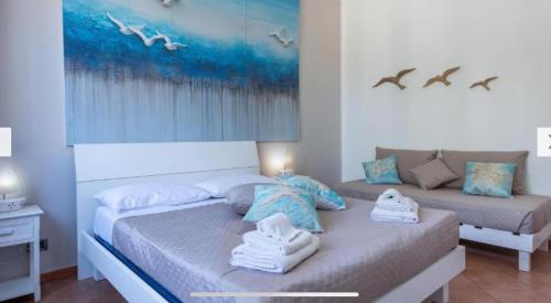 a bedroom with a bed and a couch with towels on it at Blue Coral in San Vito lo Capo