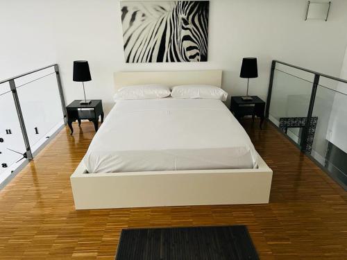 アルカラ・デ・エナレスにあるLoft Confortのベッドルーム1室(白いベッド1台付)、壁にシマウマの絵が飾られています。
