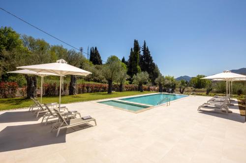 a swimming pool with two umbrellas and chairs and a pool at Stablo Residence in Kanálion