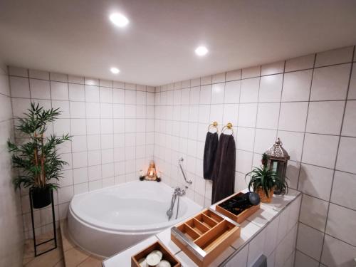 a white bathroom with a tub and plants at FeWo Pfälzer Felsenlandschaft in Pirmasens