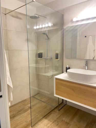 La salle de bains est pourvue d'une douche en verre et d'un lavabo. dans l'établissement BOUTIQUE HOME LIGNANO, à Lignano Sabbiadoro