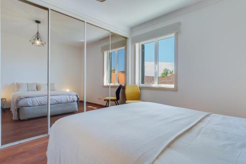 a white bedroom with a bed and two windows at Bela São Tiago I in Funchal