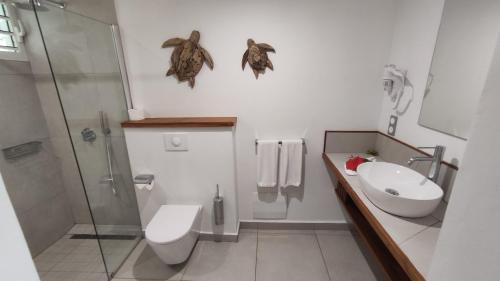 a bathroom with a toilet and a sink and a shower at Hotel - Résidence Habitation Grande Anse in Deshaies