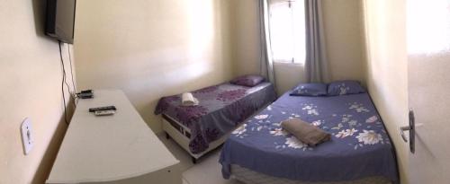 Habitación pequeña con 2 camas y mesa. en Propriedade sinta-se em casa en Piranhas
