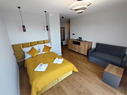 ein Schlafzimmer mit einem gelben Bett und einem blauen Sofa in der Unterkunft WIŚLANY PORT WILLA in Krynica Morska