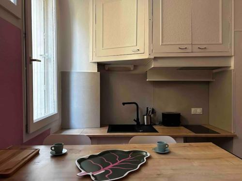 a kitchen with a table with two cups and a sink at Studio place St Didier in Avignon