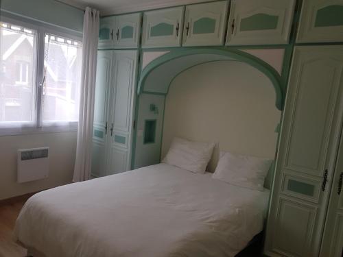 - une chambre avec un lit blanc et une arche au-dessus dans l'établissement Residence JEANNE 50 m de l'Esplanade classé 2 étoiles, à Berck-sur-Mer