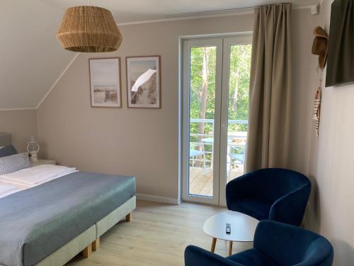 a bedroom with a bed and two chairs and a patio at Villa PortoBianco in Pobierowo