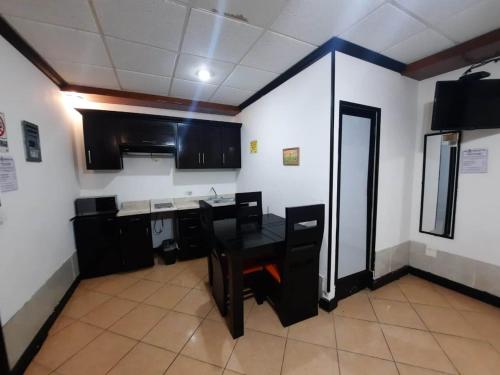 a kitchen with a black table and black cabinets at Hotel Garcias Suites, Linares in Linares