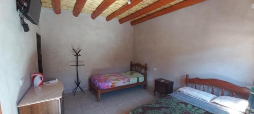 1 dormitorio con 1 cama y 1 cruz en la pared en El Shaddai en Tilcara