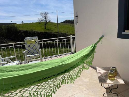 a green hammock on a patio with a table and chairs at Casa da Celeste in Vale do Pereiro