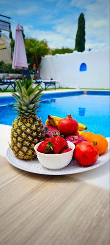 a plate of fruit on a table next to a pool at Nicole Luxury Villas in Koskinou