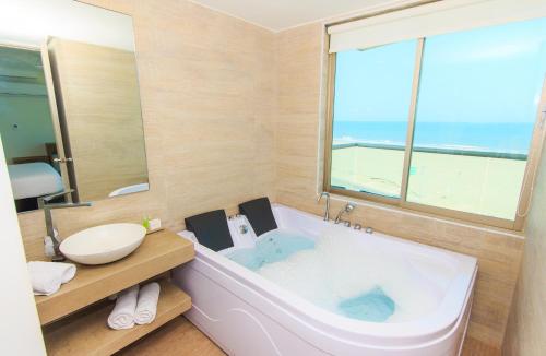 uma casa de banho com uma grande banheira e uma grande janela. em Hotel Summer Frente Al Mar em Cartagena de Indias