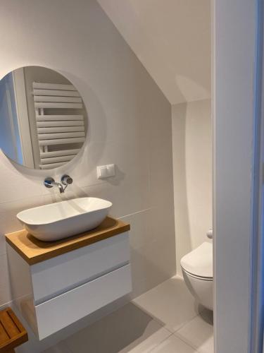 a white bathroom with a sink and a mirror at Villa PortoBianco in Pobierowo