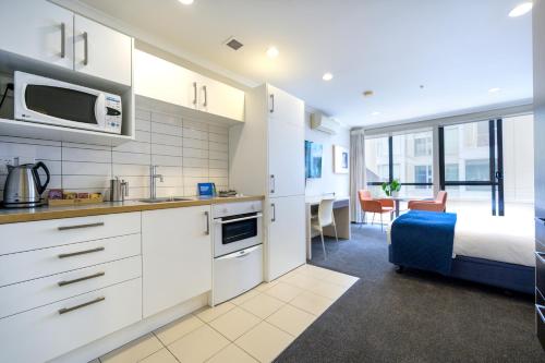 a kitchen with white cabinets and a bed in a room at U Residence Hotel in Wellington