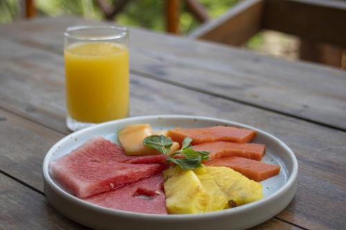 un bol de fruta y un vaso de zumo de naranja en Zenote Sanctuary, en Tulum