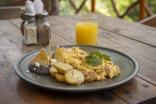 a plate of food on a wooden table with a glass of orange juice at Zenote Sanctuary in Tulum
