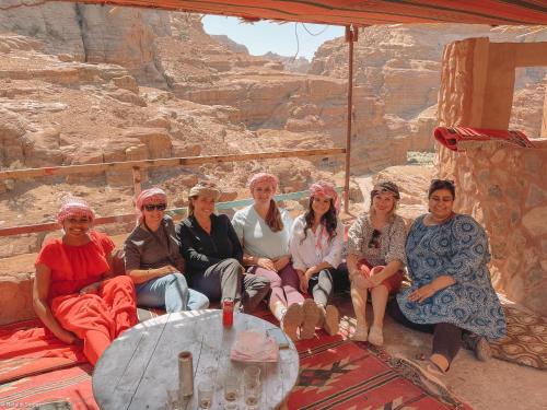 a group of women sitting around a table in the desert at Indiana Jones Cave in ‘Ayn Amūn