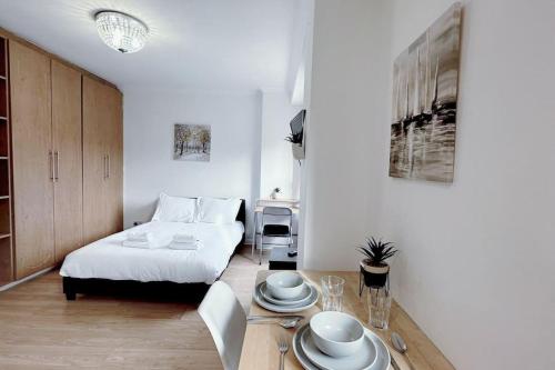 a bedroom with a bed and a table with plates on it at Charming Studio Flat with Private Patio Balcony in the Heart of Chelsea in London