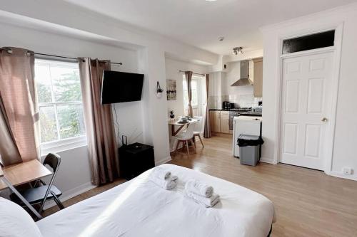 a white bedroom with a white bed and a kitchen at Charming Studio Flat with Private Patio Balcony in the Heart of Chelsea in London
