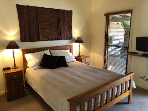 a bedroom with a large bed with two lamps and a television at Meriba B and B in Bundanoon