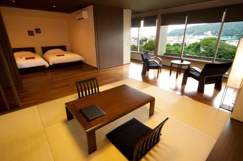 een kamer met een bed en een tafel en stoelen bij Ito Yukitei in Ito