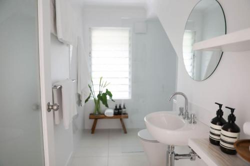 a white bathroom with a sink and a mirror at Sirens in Byron Bay