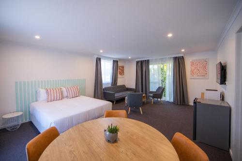 a hotel room with a bed and a table at Gosford Palms Motor Inn in Gosford