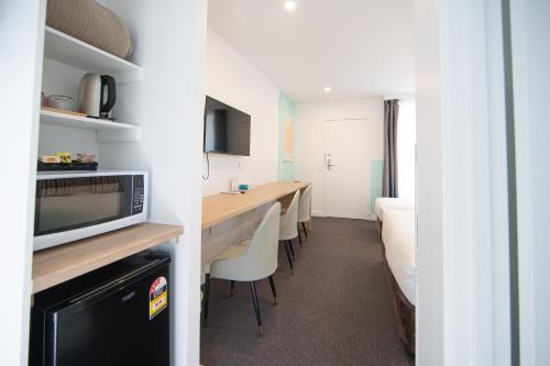 a room with a long table with chairs and a bed at Gosford Palms Motor Inn in Gosford
