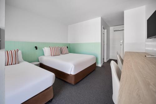 a hotel room with two beds and a tv at Gosford Palms Motor Inn in Gosford