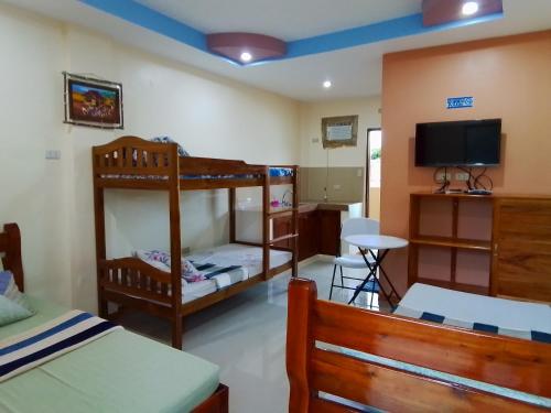 a bedroom with two bunk beds and a flat screen tv at D&D Travellers INN in Puerto Princesa City