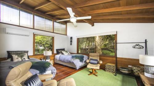 a bedroom with two beds and a couch and a fan at Oceanic Coastal Lodge Pearl Beach in Pearl Beach