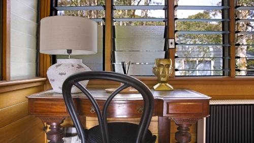 a desk with a lamp and a chair next to a window at Oceanic Coastal Lodge Pearl Beach in Pearl Beach