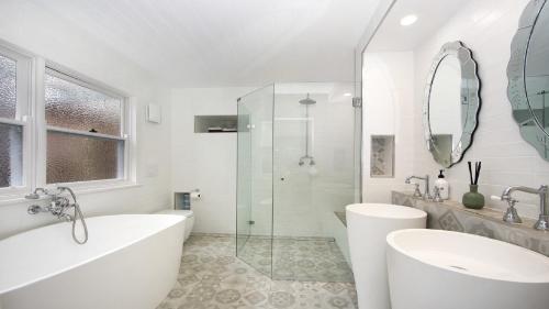 a white bathroom with a tub and a sink at Oceanic Coastal Lodge Pearl Beach in Pearl Beach