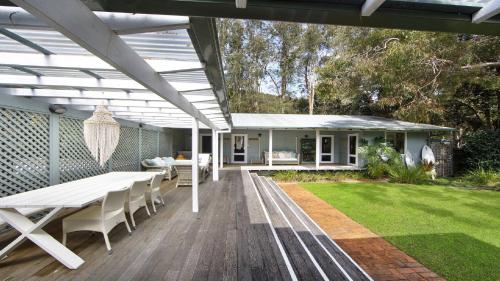 a patio with a table and chairs on a deck at Oceanic Coastal Lodge Pearl Beach in Pearl Beach