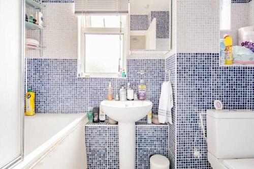 a blue tiled bathroom with a sink and a tub at Lovely and comfortable Home Stay in London in London